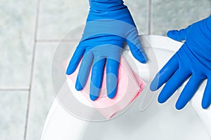 Hands in gloves clean toilet. Cleaning toilet bowl