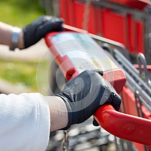 Hands, gloves on handle of shopping cart