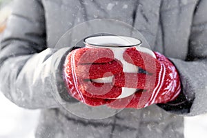 Hands in gloves holding cup