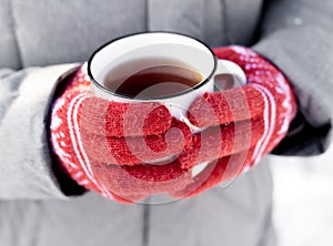 Hands in gloves holding cup