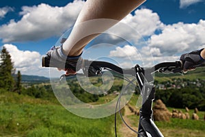 Hands in gloves holding handlebar of a bicycle. Mountain Bike cyclist riding single track. Healthy lifestyle active athlete doing