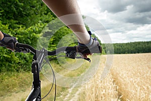 Hands in gloves holding handlebar of a bicycle. Mountain Bike cyclist riding single track. Healthy lifestyle active