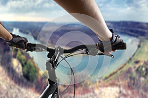 Hands in gloves holding handlebar of a bicycle. Mountain Bike cyclist riding single track. Healthy lifestyle active