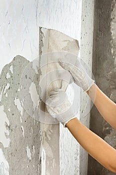 Hands in gloves removing old wallpaper