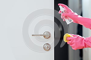 Hands in gloves spraying and polishing door handle