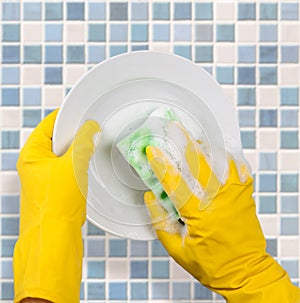 Hands in gloves washing dish on kitchen