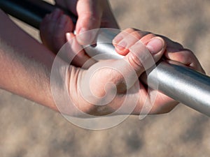 Hands grabbing steel monkey bars at a playground