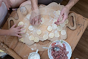 Hands of grandmother and girl, coocking dough for dumplings with meat