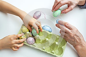 Hands of grandson and grandmother make crafts from Easter eggs. Easter concept and family traditions and pastime