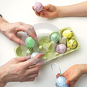 Hands of grandson and grandmother make crafts from Easter eggs. Easter concept and family traditions and pastime