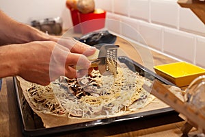 Hands grating cheese on top of pizza or flammekueche