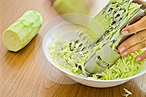 Hands grating zucchini