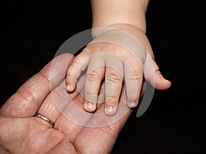 Hands of great grandma and her great baby grandson
