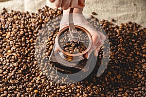 Hands grinding on a manual grinder fragrant coffee beans. Top view. Selection of fresh coffee for espresso