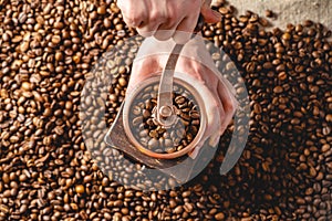 Hands grinding on a manual grinder fragrant coffee beans. Top view. Selection of fresh coffee for espresso