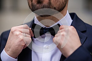 the hands of the groom bow tie. stylish groomsmen helping happy groom getting ready in the morning for wedding ceremony. luxury