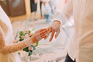 Hands of the groom and bride wearing ring on finger, wedding ceremony in registry office, close-up