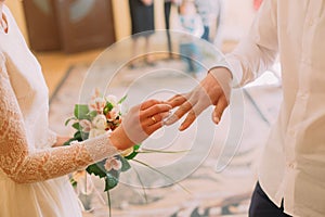 Hands of the groom and bride wearing ring on finger, wedding ceremony in registry office, close-up