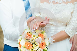 Hands of groom and bride with wedding rings and flowers roses. concept of love and marriage