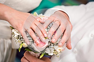 Hands of the groom and the bride with wedding rings and a wedding bouquet