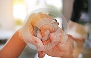 Hands of groom putting wedding ring for Bride. Close up