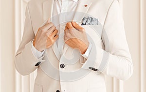 Hands of the groom in a white jacket on a white background