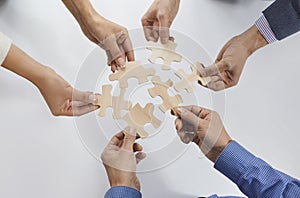 Hands of group of business people assembling jigsaw puzzle. cooperation, teamwork support concept.