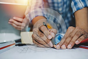 Hands of group engineer and architect working on blueprint and mobile tablet on workplace desk