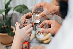 Hands of a group of friends clinking glasses of vodka