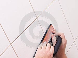 Hands grouting a ceramic tile