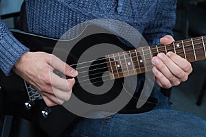 Hands of guitarist with an electric guitar pick. Abstract music background
