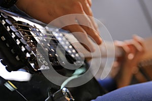 Hands of a guitarist playing a black electric guitar