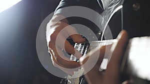Hands of guy performing solo of rock music. Close up arms of musician playing on electric guitar. Male fingers of