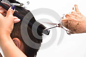 Hands of a hair stylist trimming hair with a comb and scissors