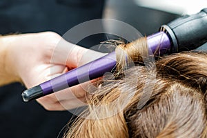 Hands of hairdreser twisting hair of woman