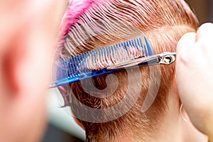 Hands cuts hair of woman