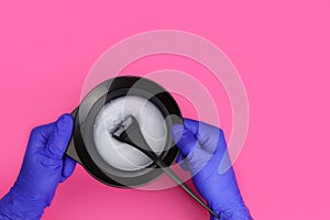 hands of the hairdresser holding hair dye with brush in color mixing bowl