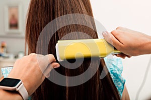 Hands of a hairdresser. The master evens out the client& x27;s hair with a curler
