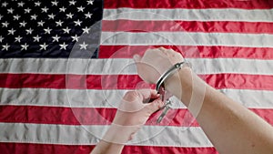 hands in handcuffs against the US flag unlocking handcuffs and putting them off