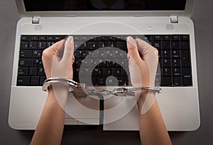 Hands and handcuffs on laptop keyboard. Cyber Crime