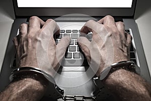 Hands in handcuffs typing on laptop keyboard internet obsession or addiction photo