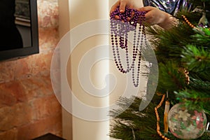 Hands hang garland on Christmas tree close up