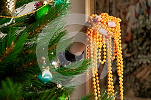 Hands hang garland on Christmas tree close up