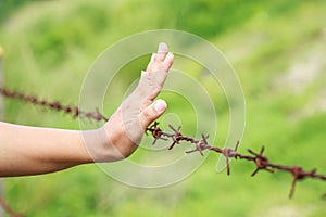 Hands hanging on old metal rusty barbed wire