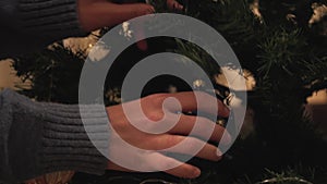 Hands of happy couple decorating the Christmas tree in the room before holiday close-up. New Year and Christmas time