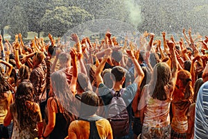 Hands and happy people crowd partying under rain at holi fest, f