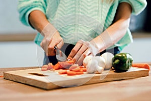 Hands of healthy young woman cutting fresh vegetables in the kitchen at home
