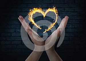 hands with heart fire icon over. Dark bricks wall background