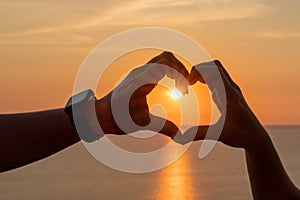 Hands heart sea sanset. Hands forming a heart shape made against the sun sky of a sunrise or sunset on a beach