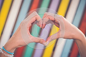 Hands in heart shape against colorful background